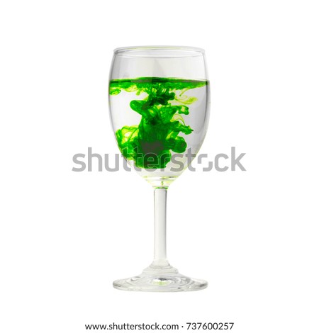 Green food coloring diffuse in water inside wine glass isolated on white background.