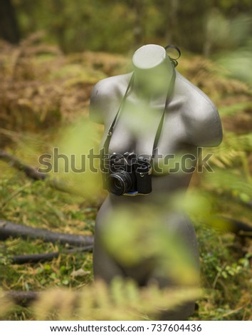 A female mannequin torso hiding in a bright green forest. Taking pictures with a camera. Vertical photo. Latvia