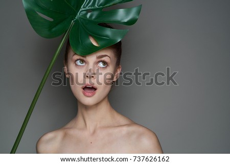 surprised woman holding a palm leaf on a black background, beauty, spa                               