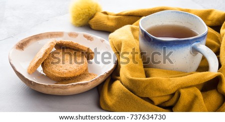 Winter comfort food concept with woman's scarf, mug of tea and cookies. Moment of relax