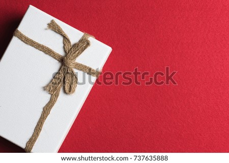 White gift box, ribbon bundle, cotton rope, placed on a red background.