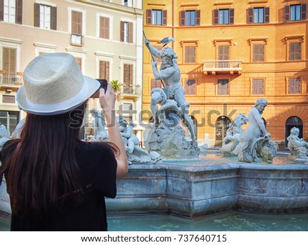 Girl takes a picture of the Fountain of Neptune (Fontana del Nettuno) in the Piazza Navona in Rome, Italy. 