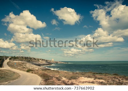 Sea landscape, blue sky with white fluffy clouds, and winding coastal road. Vieste, Puglia, Italy.