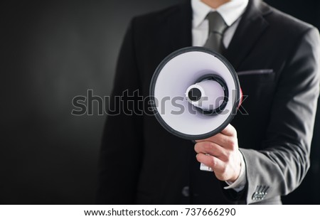 Close up of businessmans hand holding megaphone over dark background Royalty-Free Stock Photo #737666290