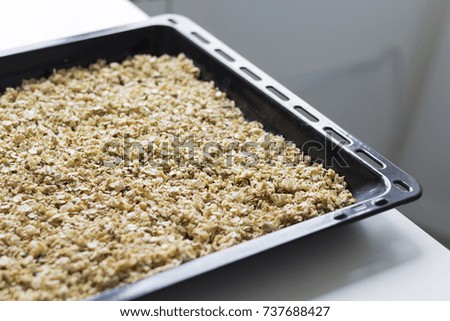 Granola in the oven tray on the white table, close-up