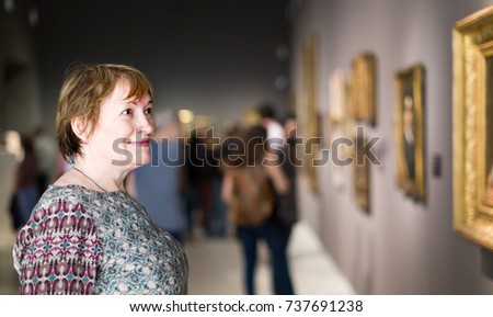 pensioner woman watching at art collection exhibition in museum