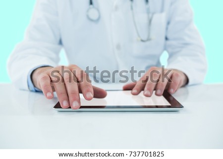 Doctor using digital 3D tablet against white background against blue vignette background