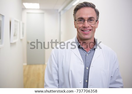 Portrait of smiling dentist standing at lobby in dental clinic Royalty-Free Stock Photo #737706358