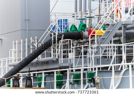 Rubber hose connect to tanker vessel loading liquid cargo at port. Liquid cargo loading discharging concept Royalty-Free Stock Photo #737721061