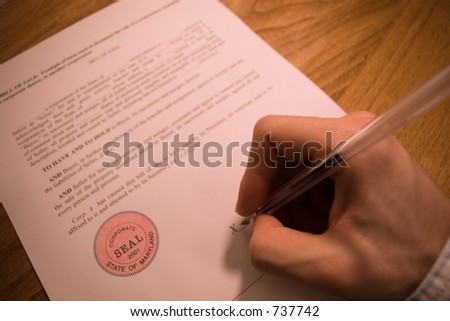 person's hand signing a contract bill of sale.