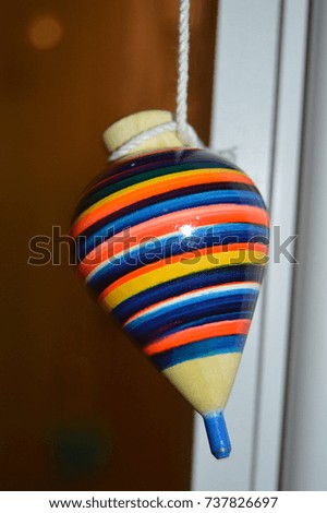 front view look of a children adult vintage old antic toy handmade colorful hanging from a rope with a window on the background 