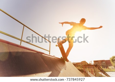 Teen skater hang up over a ramp on a skateboard in a skate park