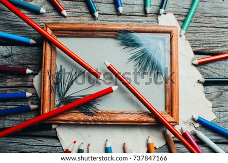 Christmas composition ,photo frame on wooden table, with branches of trees around the scattered pencils of different colors