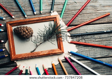 Christmas composition, photo frame on wooden table, tree branches and cones scattered around different colors