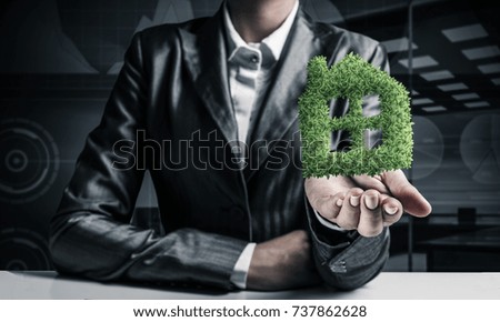 Cropped image of businessman in black suit presenting empty palm with dark office view on background.