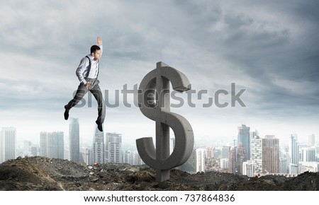 Jumping businessman in smart casual wear crashing big dollar symbol with city view on background.