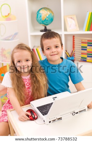 Little boy and girl with laptop computer in their room smiling to the camera