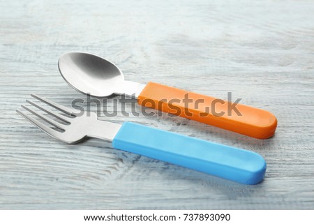 Colorful eating utensils for baby on wooden table