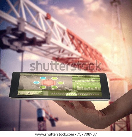 Human hand holding digital tablet against white background against 3d image of red and yellow cranes