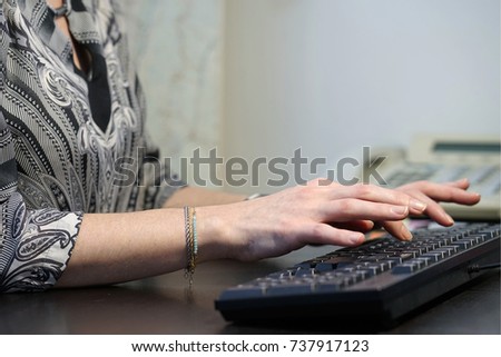Cute business woman working on the computer.The office worker prints on the keyboard.  Female hands on the keyboard