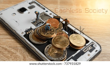 Three miniature mini  figures with keep money in mobile. Cashless Society Concept pay with Application mobile phone. Wording Cashless Society on background