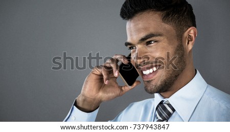 Smiling businessman talking on mobile phone against grey background