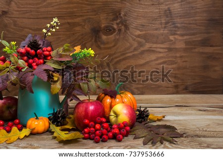 Fall table centerpiece with rowan berries and leaves in turquoise vase, pumpkins, apples, cones, copy space