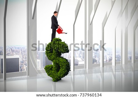 Businessman holding red watering can against room with large window looking on city
