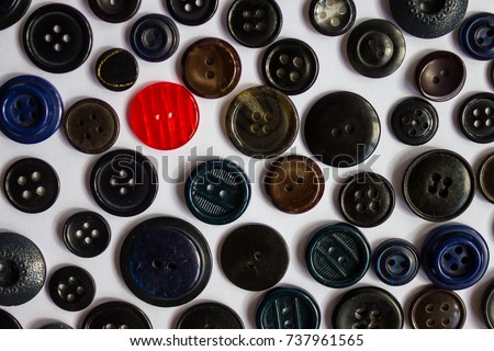 Many black buttons of different sizes and types. In the middle one is red. Accessories for sewing clothes, goods for handwork.  