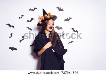 girl in costume on halloween laughing surrounded by bats