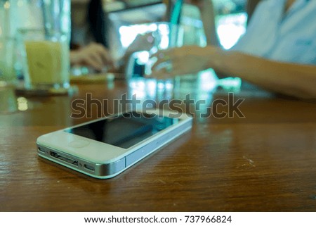 Smart phone on wooden table at a coffee shop