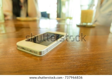 Smart phone on wooden table at a coffee shop