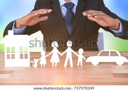 underwriter protecting family in paper with his hands against grass under a sunny sky