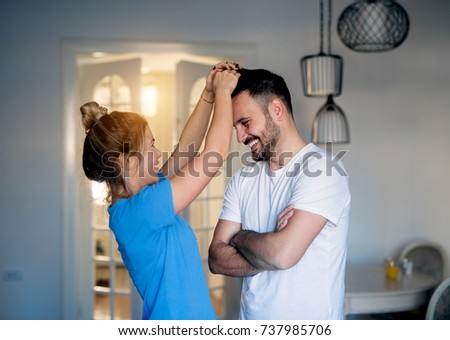 Cheerful pretty girl making hairstyle to her boyfriend in the morning.