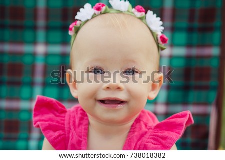 Cute baby blond girl child wearing pink dress sitting in green park nature on brown old fashion retro bag trunk with teddy bear friend.
