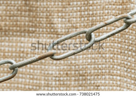 Old rusty metal chain on sackcloth background. Selective focus