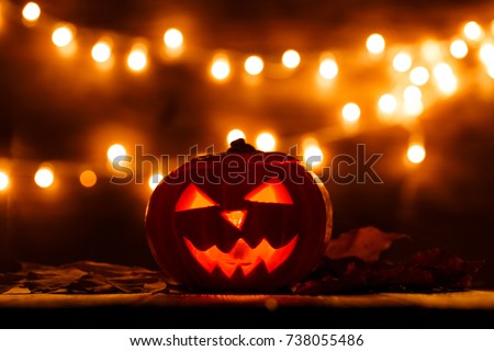 Photo of halloween pumpkin cut in shape of face on background with burning yellow lights