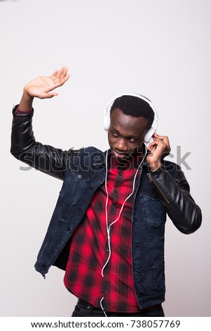 excited african american man listening music in headphones and dancing isolated on white
