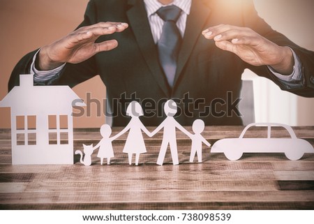 underwriter protecting family in paper with his hands against bright room with wall in the middle