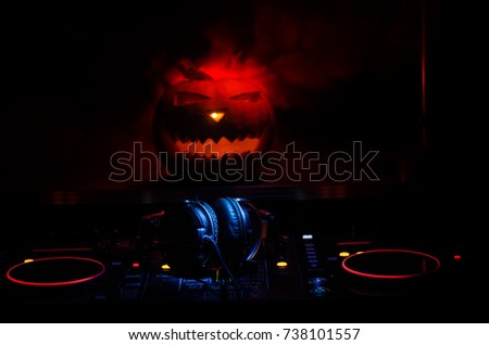 Halloween pumpkin on a dj table with headphones on dark background with copy space. Happy Halloween festival decorations and music concept