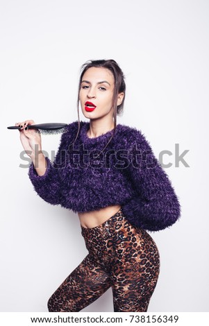 young brunette girl with nice body posing in a photo Studio. body after diet. emotional portrait. street style in clothes: tight pants and a colorful sweater. clear skin and healthy hair