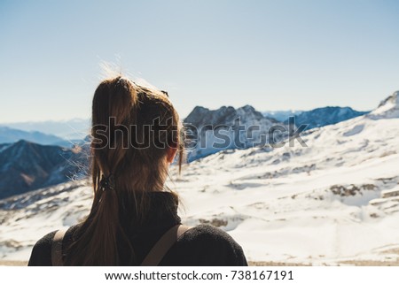 Girl from behind looking over snowy alps