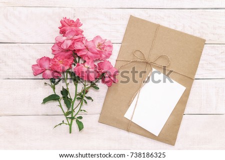 Blank white greeting card with brown envelop in craft paper  and daisy flowers on wooden pink table with vintage tone. Rustic background