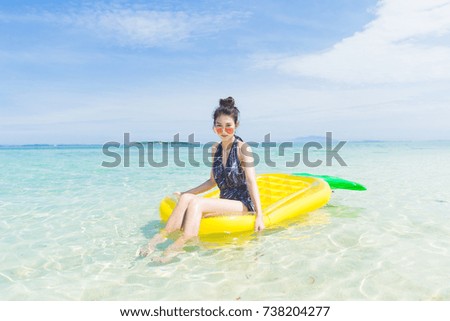 Young pretty Woman swimming with inflatable big pineapple on the beach in summer sunny day at  munnork private Island Thailand