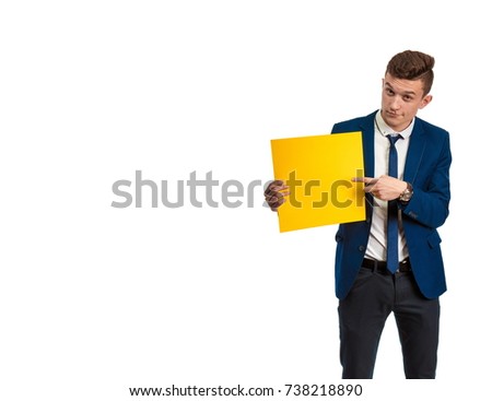 Young guy in blue suit holding in hands yellow sheet of paper for notes and posing against white background