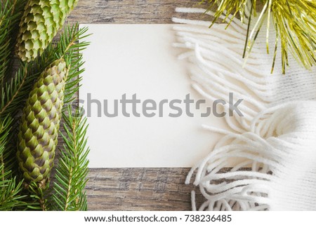 White blank greeting card with beautiful, fresh, green pine cones and scarf. Mock up for holiday post card and seasonal offers as advertising or other ideas. Empty place for a text.