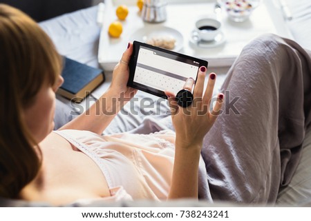 Lazy sunday morning. Woman using tablet in bed.