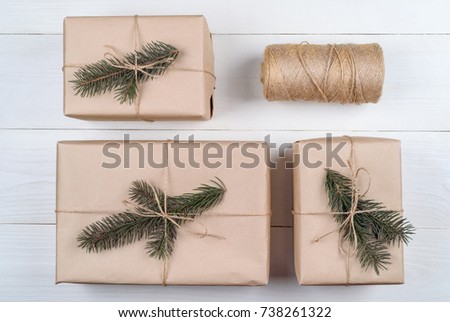 Christmas background with gift boxes wrapped in kraft paper with fir tree branches on white wooden background, free space. Holiday greeting card, copy space. Flat lay, top view 