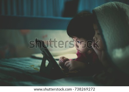 two asian children watching tablet  / playing phone and looking at cartoon / kid play tablet
