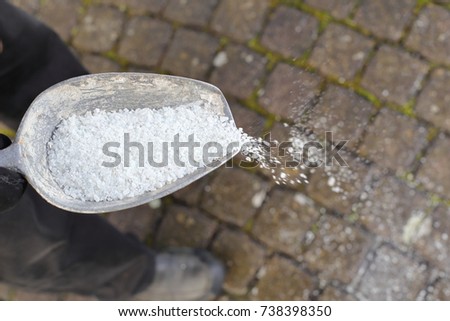 A Man spreading de-icing salt on a path in winter